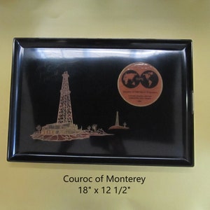 May include: Black lacquered tray with a gold-colored image of an oil rig and a globe. The tray is 18 inches by 12 1/2 inches and has the text "Couroc of Monterey" on the bottom.