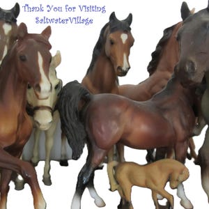 May include: A group of eight miniature horse figurines, including a grey horse, a brown horse, a white horse, and a brown and white horse. The horses are arranged in a circle, with their heads facing the centre. The text "Thank You for Visiting Saltwater Village" is written above the horses.