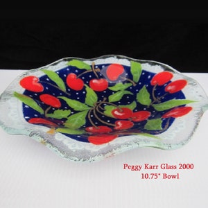 May include: A glass bowl with a blue background and white polka dots. The bowl is decorated with a cherry motif and has a scalloped edge. The bowl is 10.75 inches in diameter. Peggy Karr Glass 2000.
