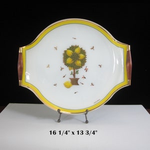 May include: A white porcelain serving tray with a gold rim and wooden handles. The tray features a hand-painted lemon tree with yellow lemons and green leaves. The tray measures 16 1/4" x 13 3/4".