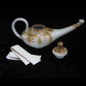 May include: A white ceramic oil lamp with a brown glaze. The lamp has a spout and a handle. It comes with a white wick and a brown ceramic lid.