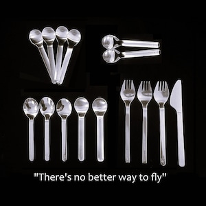May include: A collection of clear plastic cutlery including nine spoons, three forks, and one knife arranged in groups. The text "There's no better way to fly" is printed at the bottom. The set features a smooth, transparent finish on all pieces.
