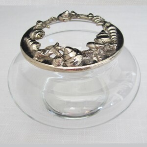 May include: A clear glass jar with a silver lid decorated with seashells and starfish.