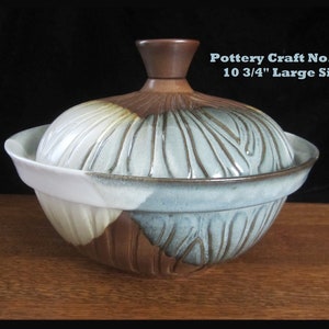 May include: A large, blue and brown ceramic serving bowl with a lid. The bowl has a wood knob on the lid. The bowl is 10 3/4" in diameter. Pottery Craft No. 552.