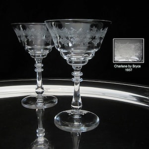 May include: Two clear glass cocktail glasses with etched floral designs on a silver tray. The glasses are part of the Charlene pattern by Bryce, made in 1937.