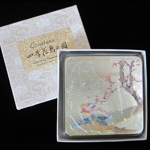 May include: A set of four coasters with a Japanese-inspired design featuring a bird and a flowering tree branch. The coasters are in a white box with the text "Coasters" and "春花鳥の図" in gold lettering.