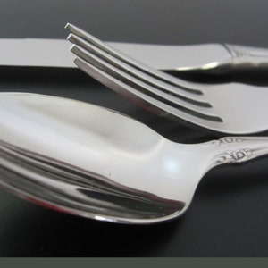 May include: A set of silverware with a spoon, fork, and knife. The silverware is made of polished stainless steel and has a traditional design.