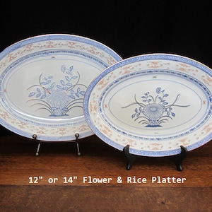 May include: Two oval porcelain platters with blue and red floral designs. The platters are 12" or 14" in diameter and are called "Flower & Rice Platter".