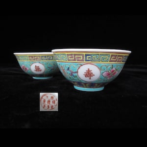 May include: Two small blue and white porcelain bowls with Chinese characters and floral designs. The bowls have a gold rim and are decorated with a traditional Chinese pattern.