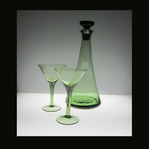 May include: A set of three green glass pieces: a decanter with a black stopper and two martini glasses.