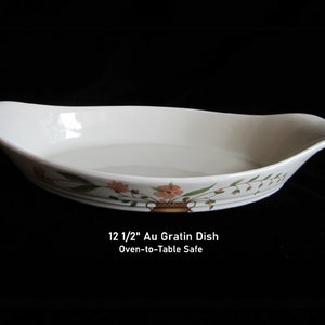May include: White oval Au Gratin dish, 12.5 inches long, with a floral design in orange, green, and brown. The dish has curved handles and is oven-to-table safe.