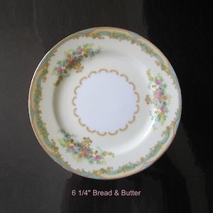 May include: A 6 1/4 inch white porcelain bread and butter plate with a gold and green floral design.
