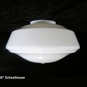 May include: A white, schoolhouse-style light fixture with a rounded top and a flared, geometric shade. The fixture is 16 inches in diameter and has a smooth, glossy finish. The text "16" Schoolhouse" is visible at the bottom.