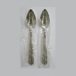 May include: Two silver grapefruit spoons, each in a clear plastic wrapper. The spoons have a fluted handle design and a serrated edge on the spoon bowl. The spoons are designed for serving grapefruit.
