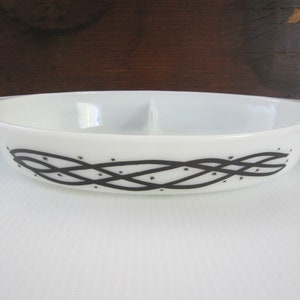 May include: White divided casserole dish with black and white design. The design features a black braided pattern with white stars.