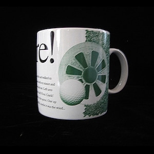 May include: White ceramic mug with a golf theme. The mug features a green and white design of a golf ball and a golf course element. The word "re!" is printed on the mug, along with some text.