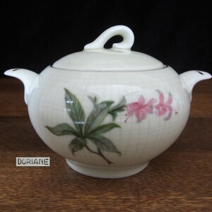 May include: White ceramic sugar bowl with a lid and a floral design. The design features pink flowers and green leaves.