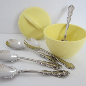 May include: A collection of vintage serving pieces. Includes a pale yellow bowl and lid, four silver serving spoons with shell-shaped bowls, and a small silver spoon inside the bowl. The spoons have ornate handles.