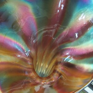 May include: A iridescent glass vase with a funnel-shaped opening. The vase has a swirling pattern of pink, blue, and green.