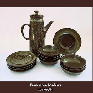 May include: A dark brown ceramic coffee pot, plates, and bowls. The coffee pot has a handle and a spout. The plates and bowls are stacked. The set is from the Franciscan Madeira collection, produced between 1967-1983.