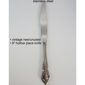 May include: A silver hollow place knife with an ornate handle. The knife is 9 inches long and is new and unused. It is part of the Brahms pattern by Oneida Community.