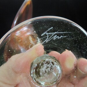May include: The bottom of a clear glass sculpture with a signature etched into the glass. The signature reads "Stan".