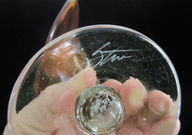 May include: The bottom of a clear glass sculpture with a signature etched into the glass. The signature reads "Stan".