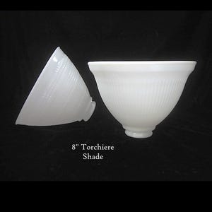 May include: Two white glass 8-inch torchiere shades. One shade is whole, the other is cut in half. The shades have a ribbed texture and a flared shape, suitable for a lamp. The text "8" Torchiere Shade" is visible.