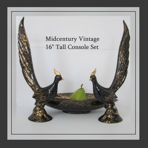 May include: A set of two black and gold ceramic bird-shaped console stands with a matching black and gold bowl. The stands are 16 inches tall and feature a gold speckled finish. Midcentury Vintage 16" Tall Console Set.