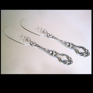 May include: A white ceramic mug with a black handle and the text "But First, Coffee" in a bold, black font. The mug is set against a neutral background, highlighting its simple design.