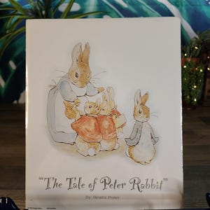 May include: A book cover featuring an illustration of Peter Rabbit and his family. The title "The Tale of Peter Rabbit" is displayed in a decorative font, with the author's name below. The artwork depicts the rabbits in various outfits.