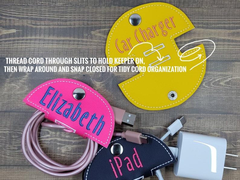 May include: Three cord organizers made of fabric with snap closures. The organizers are yellow, pink, and black. The yellow organizer has the text "Car Charger" embroidered on it. The pink organizer has the text "Elizabeth" embroidered on it. The black organizer has the text "iPad" embroidered on it.