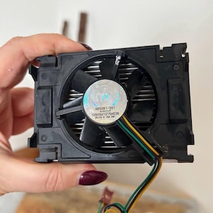 May include: Black computer CPU fan with a central fan and a heat sink. The fan has a sticker with the Intel logo and the text "A65061-001 020221P 109X5412T5H036 DC12V 0.16A PAT". Wires extend from the fan.