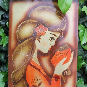 May include: A vintage painting on wood panel depicting a woman with long brown hair wearing a red dress and holding a red and white animal in her hands. The woman has a flower in her hair and is looking down at the animal.