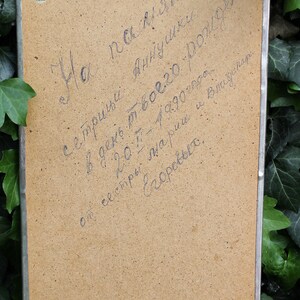 May include: A close-up of a brown cardboard surface with handwritten text in blue ink. The text reads: "На память с тридцати -  в  день твоего рождения, 20.7 - 1990 года. от сестры  Аннушки и Видинит  Езоревых."