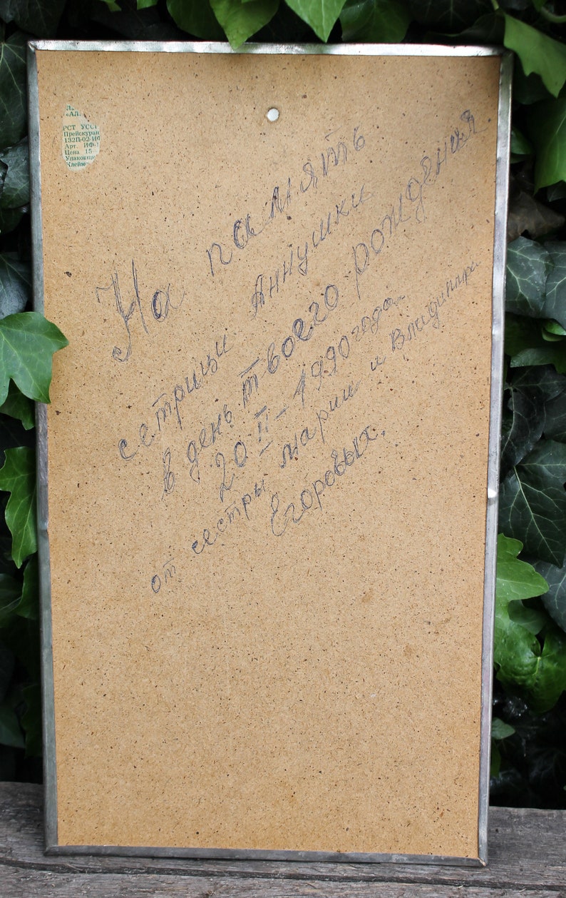 May include: A close-up of a brown cardboard surface with handwritten text in blue ink. The text reads: "На память с тридцати -  в  день твоего рождения, 20.7 - 1990 года. от сестры  Аннушки и Видинит  Езоревых."