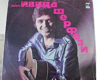 May include: A vintage vinyl record album cover featuring a man with a guitar. The album title is "Иван  Вербич" in pink lettering. The album cover is a dark brown color with a purple hue.