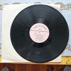 Puede incluir: Un disco de vinilo negro con una etiqueta rosa. La etiqueta tiene el texto "Мелодия" en escritura cirílica y el texto "Soviet Songs For Children" en inglés. El disco está en una funda de papel blanco.