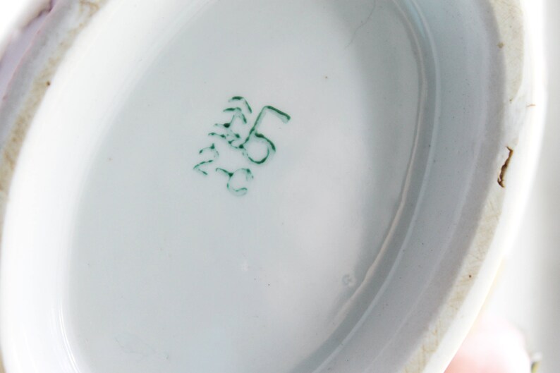 May include: Close-up of the underside of a white porcelain dish with a green mark that reads "5" in a circle.
