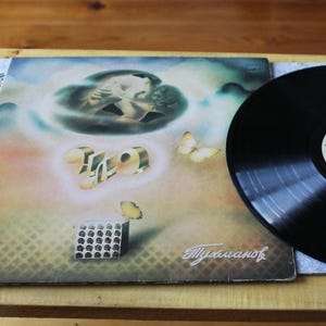 May include: A vintage vinyl record album cover with a psychedelic design featuring a couple embracing in a cloud, butterflies, and the word "Zoo" in a stylized font. The album is titled "Billy Sheehan".