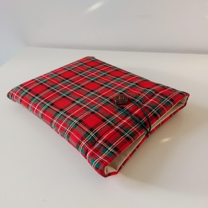 May include: Red and green plaid fabric notebook cover with a brown button closure.