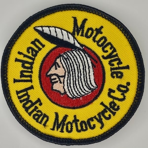 May include: Embroidered patch with a yellow background and black border. The patch features the words "Indian Motorcycle Co." in black, surrounding a red circle with a Native American profile. The profile has white hair and a feather.