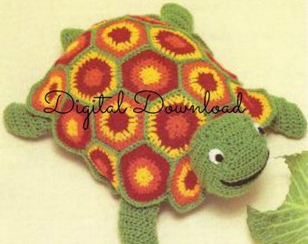 Puede incluir: Juguete de tortuga de crochet con una concha colorida hecha de hexágonos en tonos de rojo, naranja y amarillo. La tortuga tiene una cabeza y patas verdes.