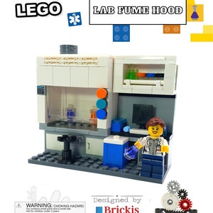 May include: A white LEGO® model of a lab fume hood with a scientist figure inside. The hood has a clear glass front, a white interior, and a blue and white ventilation system. The scientist figure is wearing a white lab coat and blue trousers. The model is designed by Brickis and includes the text "LEGO® LAB FUME HOOD".