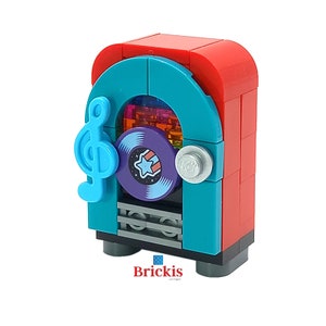 Op de afbeelding: Een rode en turquoise LEGO-jukebox met een zilveren knop en een blauwe viool-sleutel. De jukebox heeft een paarse plaat met een witte ster en een regenboogachtergrond.