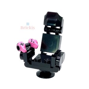 Peut inclure: Un fauteuil de jeu LEGO noir avec une manette rose de chaque côté. Le fauteuil a un dossier et une base pivotante.