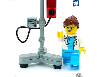 May include: A LEGO® minifigure of a female doctor wearing a white coat, blue scrubs, and a stethoscope. The doctor is standing next to a LEGO® IV stand with a red IV bag. The IV stand has a base with three legs and a black cord. The background is white with the words "LEGO®" and "HOSPITAL" in black text. The text "WARNING: CHOKING HAZARD" is also visible in the image.