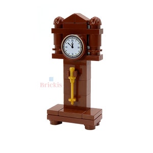 Puede incluir: Una torre de reloj Lego marrón con una esfera blanca y agujas negras. La esfera del reloj tiene números romanos y una pequeña llave dorada que cuelga del lado.