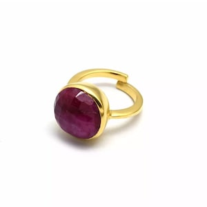 Può includere: Un anello d'oro con una grande pietra preziosa di rubino sfaccettata di forma ovale.