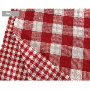 May include: Red and white gingham fabric with a checkered pattern. The fabric is folded in half, showing both sides of the pattern.